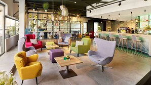 A modern lounge area with various seating options, a bar, and a well-stocked bookshelf. - Park Inn by Radisson Hasselt (Hasselt)