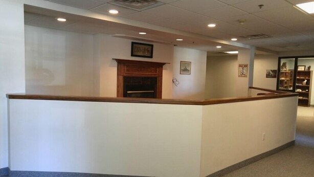 A reception area with a wooden counter, a fireplace, and a framed picture on the wall.