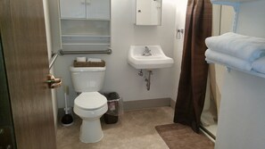 A small bathroom with a toilet, sink, and shower.