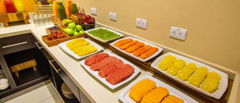 Um buffet com diversas frutas e sucos.