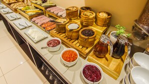 Un buffet proposant une variété de plats, notamment des viandes, des fromages et des fruits.