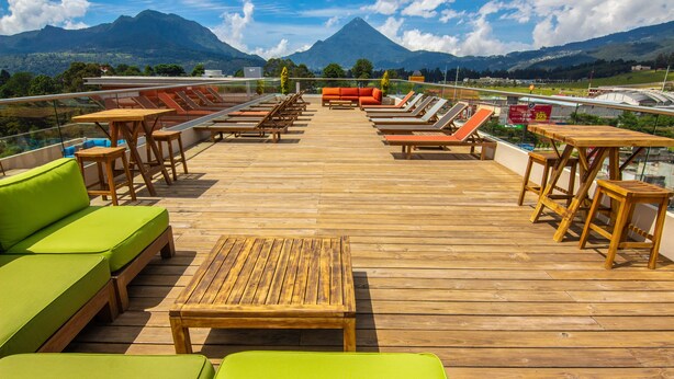 Une terrasse en bois avec des chaises longues et un canapé, offrant une vue sur un paysage montagneux.