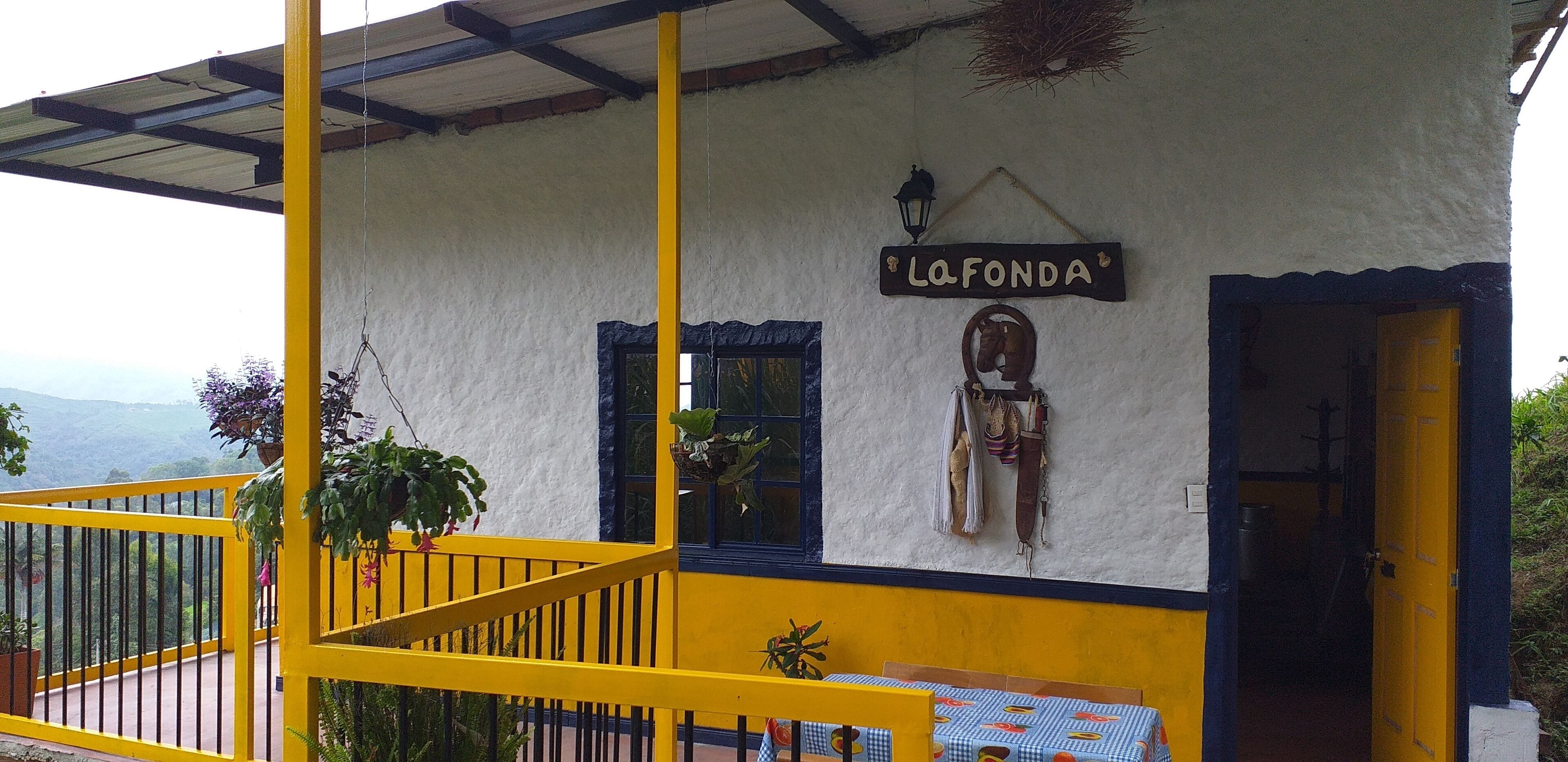 A building with a sign reading "La Fonda" and a staircase leading to a balcony with yellow railings.