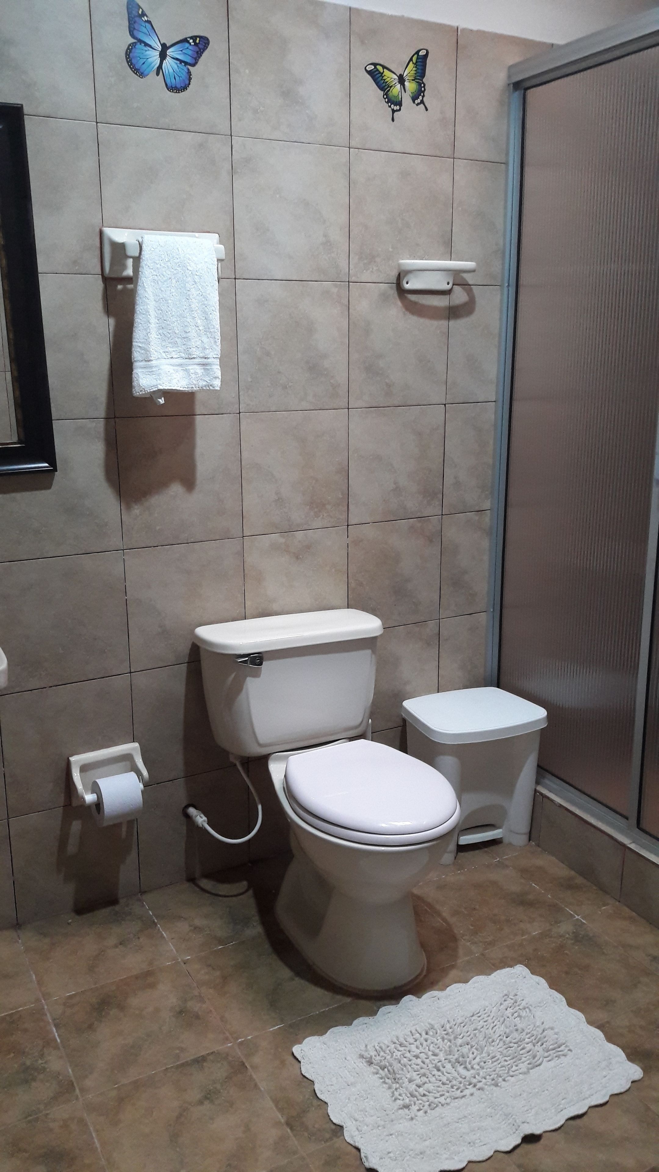 Un baño con dos inodoros, un perchero para toallas y un dispensador de papel higiénico.