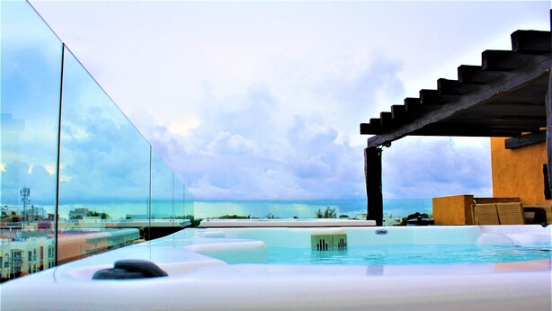 A rooftop infinity pool with a view of the ocean and cityscape. - Amazing 2BR PH steps distance from 5th Av by Happy Address (Playa del Carmen)