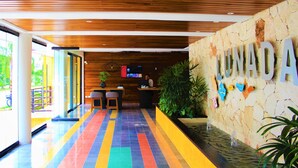 A reception area with a wooden ceiling, a colorful tiled floor, and a stone wall with the name 'LUNADA'. - Amazing 2BR PH steps distance from 5th Av by Happy Address (Playa del Carmen)