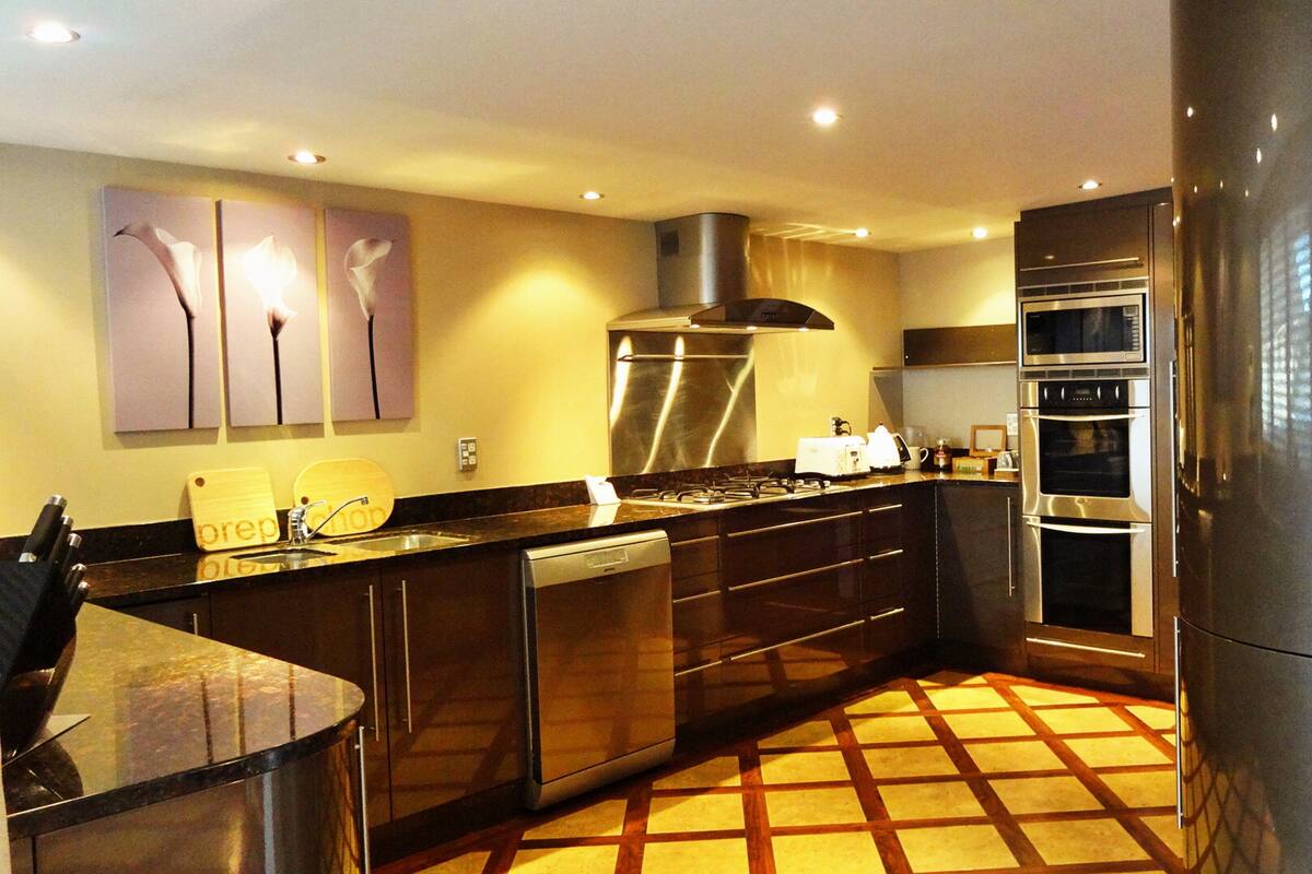 A modern kitchen with stainless steel appliances, a dishwasher, and a tiled floor.