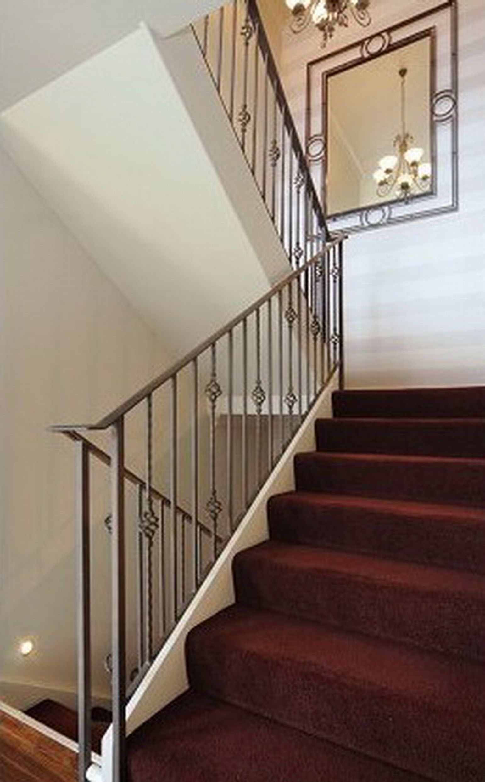 Una escalera con barandilla de metal y un candelabro.
