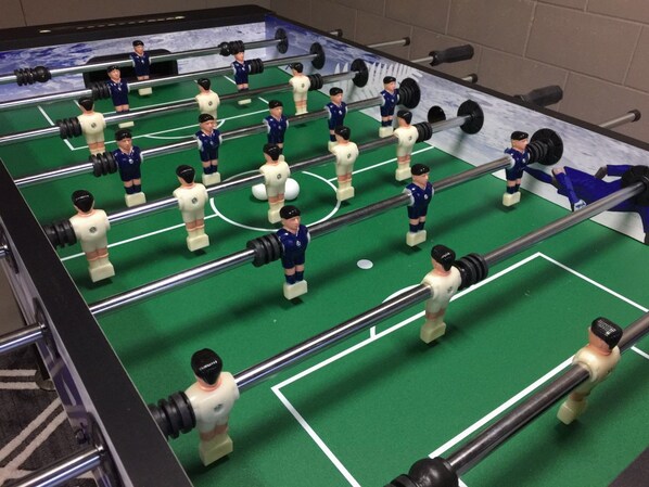 Une table de baby-foot avec plusieurs joueurs et plusieurs buts.