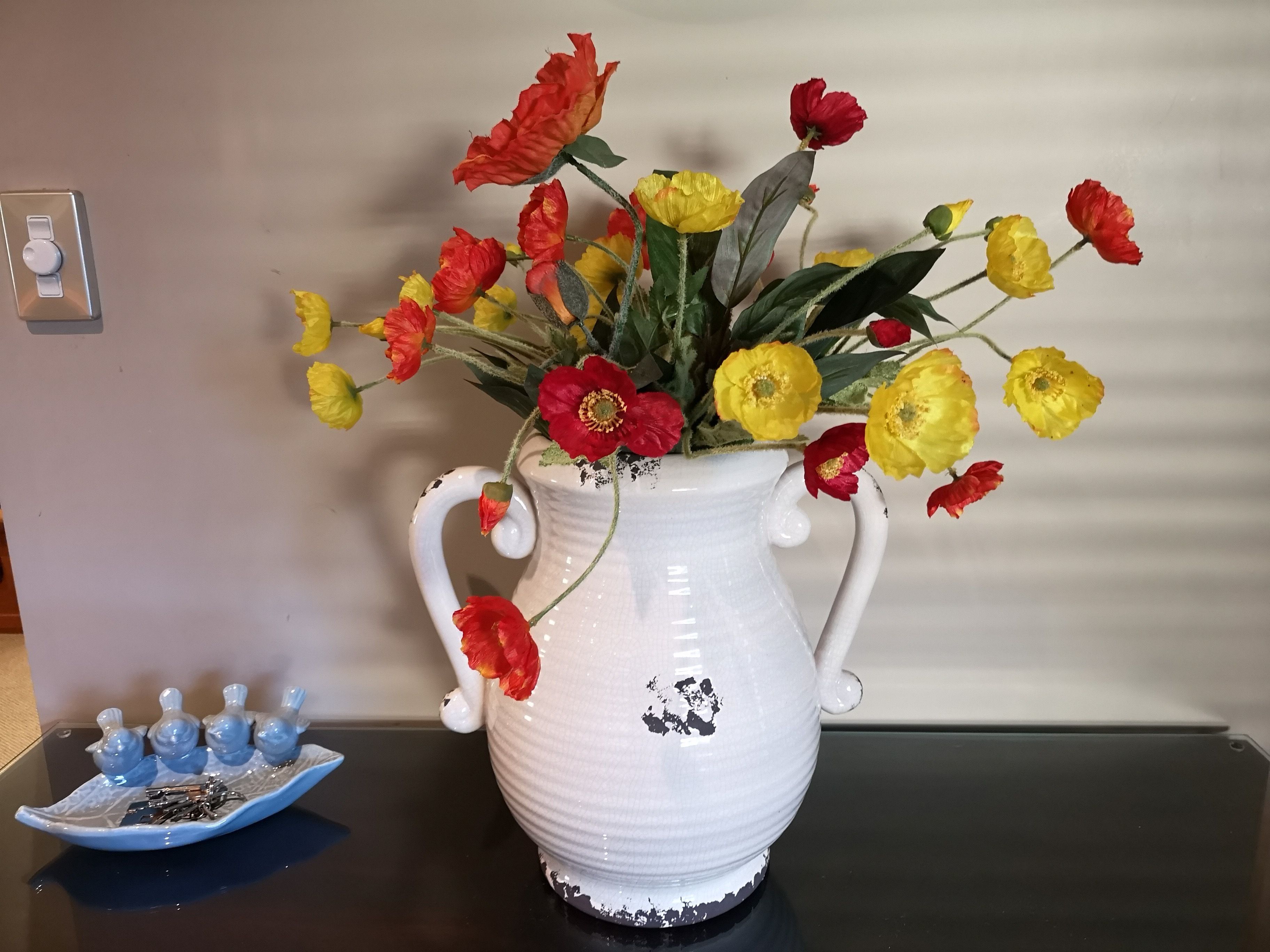 A white ceramic vase with a floral design, placed on a black table.