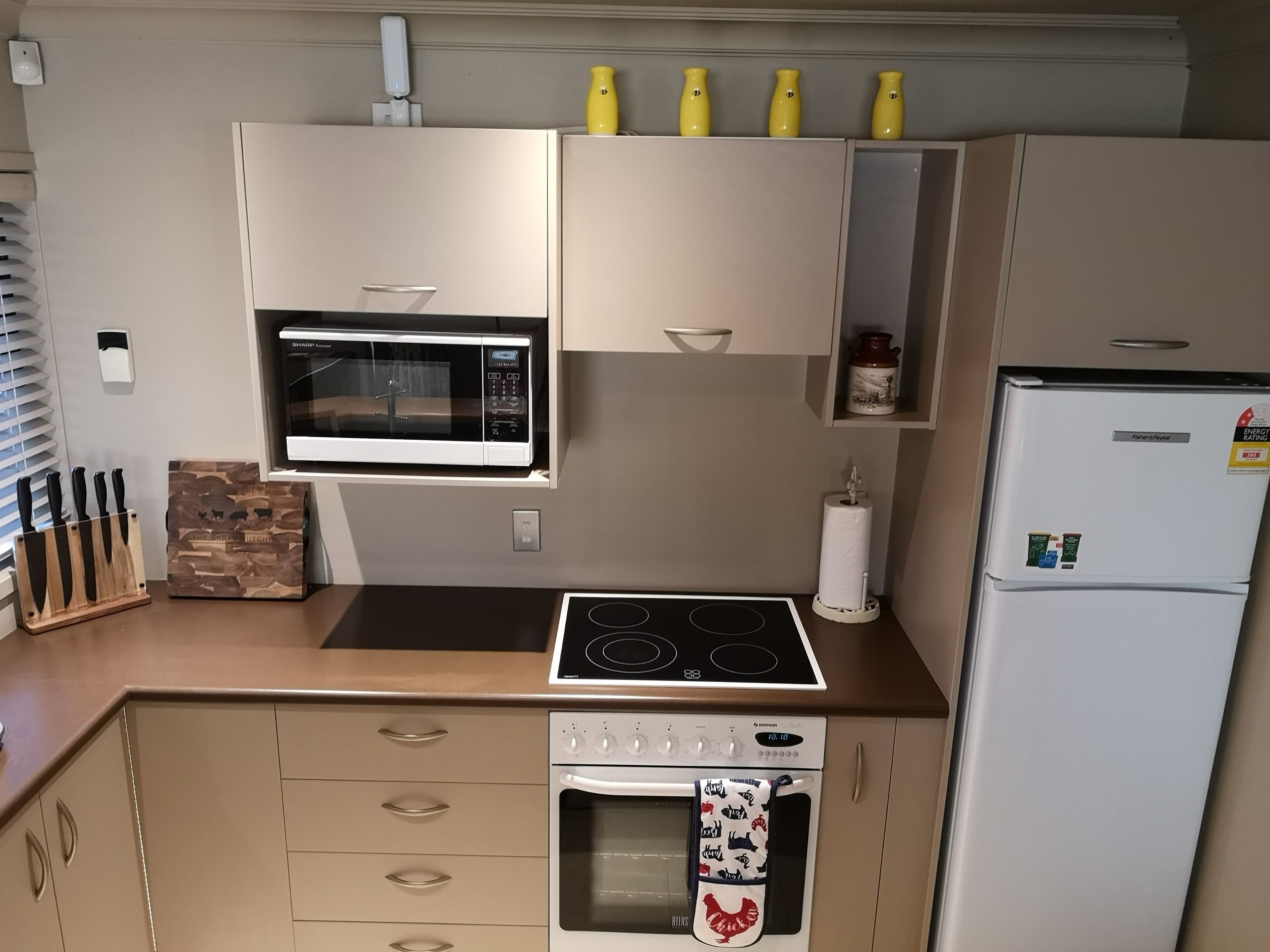 Een kleine keuken met een magnetron, fornuis, oven en koelkast.