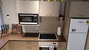 Een kleine keuken met een magnetron, fornuis, oven en koelkast.