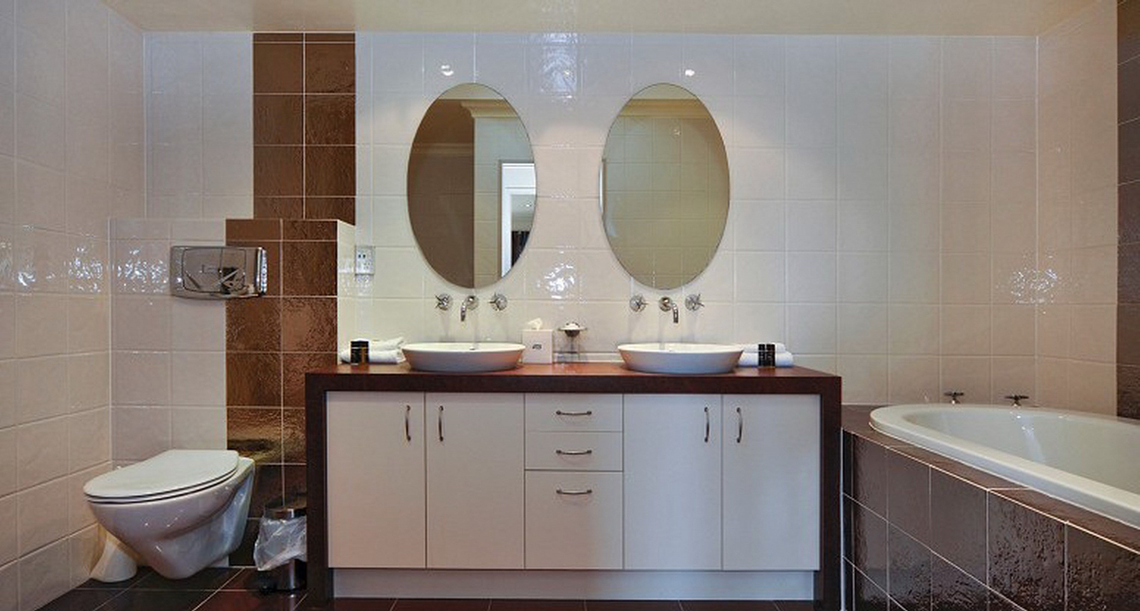 Un baño moderno con dos lavamanos, un inodoro y una bañera.