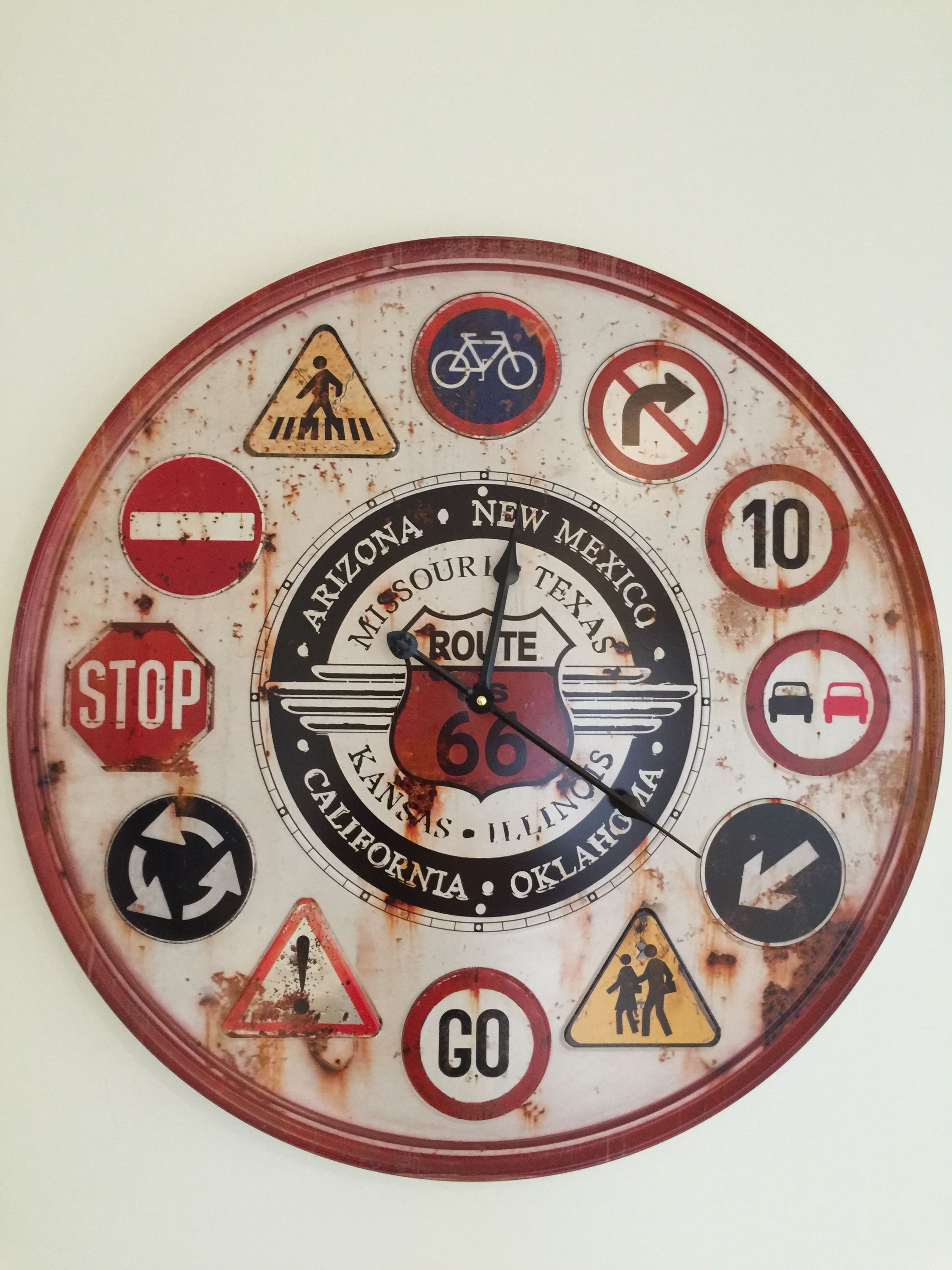A wall clock with various road signs and symbols, including a stop sign, a bicycle, and a speed limit sign.