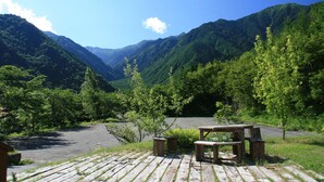 A wooden deck with benches overlooking a valley with mountains in the background. - Guesthouse Hilltop (Kiso)