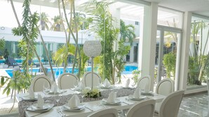 A dining area with a pool view, white table settings, and tropical plants. - Nonna Mia (Campeche)