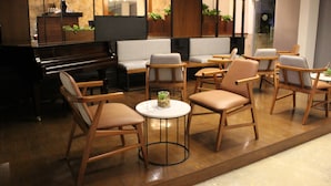A modern lounge area with a piano, comfortable seating, and decorative plants. - Nonna Mia (Campeche)