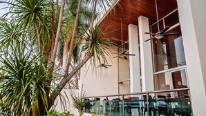 A modern building with glass railings, ceiling fans, and lush greenery. - Nonna Mia (Campeche)