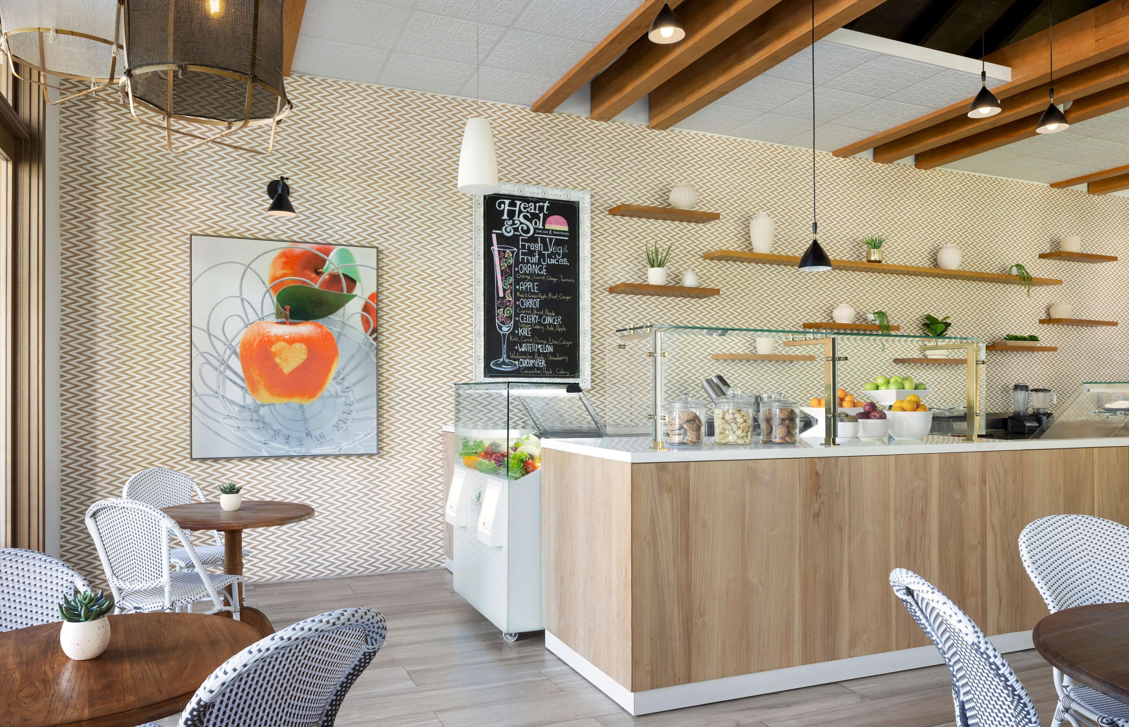 A cafe with a wooden counter, white chairs, and a chalkboard menu.