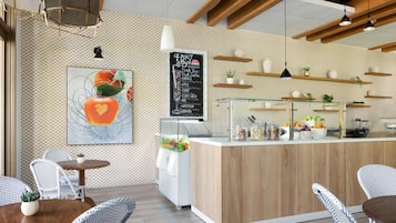 A cafe with a wooden counter, white chairs, and a chalkboard menu.