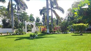 A well-maintained lawn with a white archway and palm trees in the background. - Executive Mamme Bay Hotel and Conference (Ocho Rios)