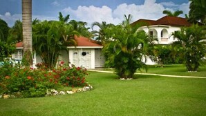 A white building with a red roof, surrounded by lush greenery and palm trees. - Executive Mamme Bay Hotel and Conference (Ocho Rios)