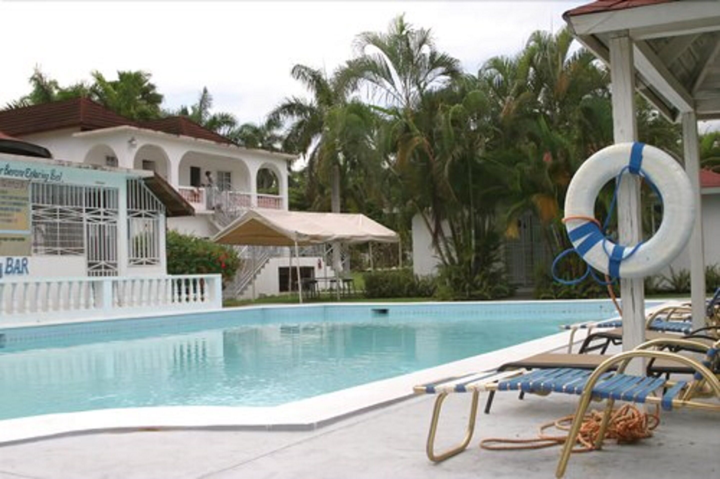 A swimming pool with lounge chairs and a lifebuoy.