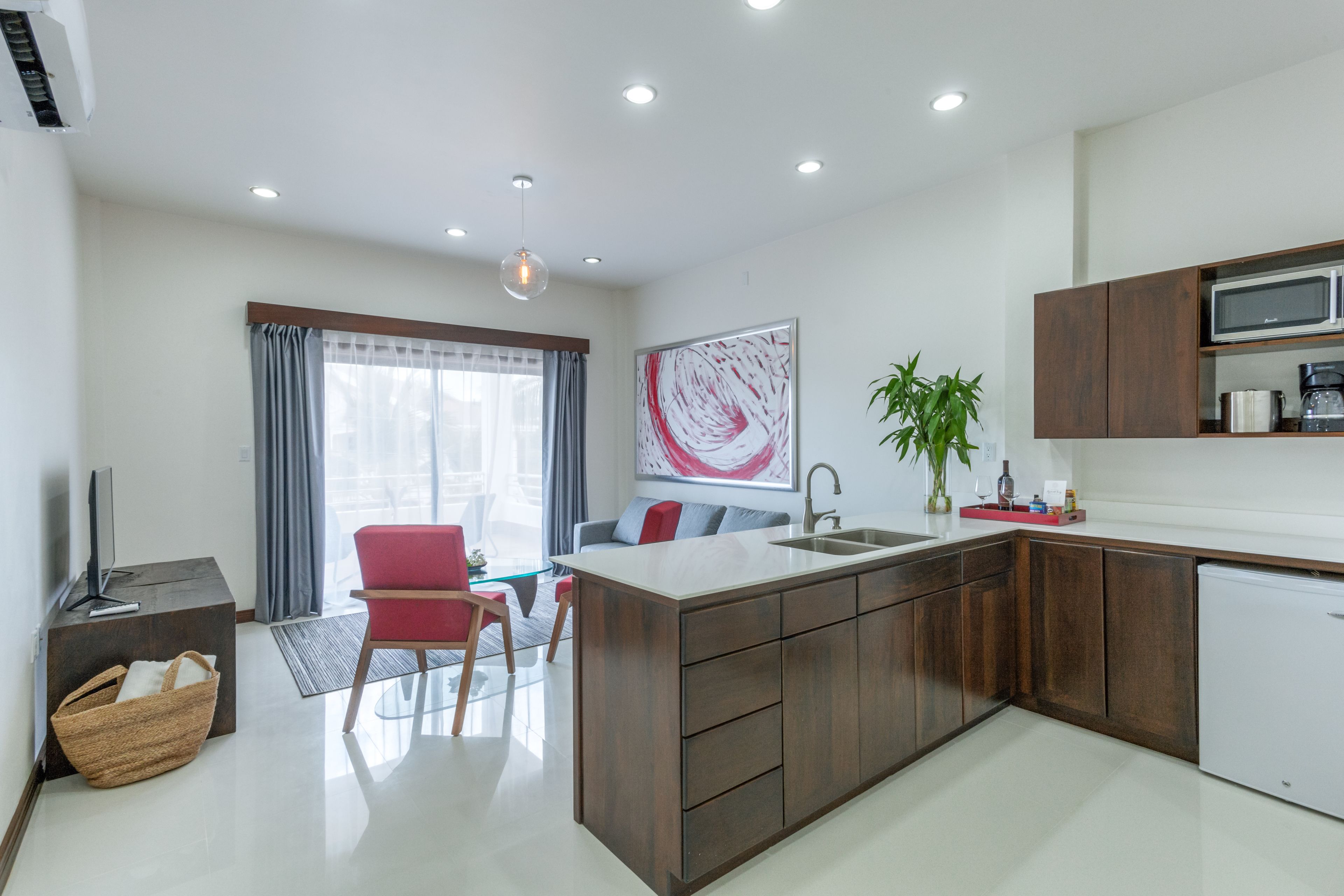 A modern kitchen with a central island, wooden cabinets, a microwave, and a sink.