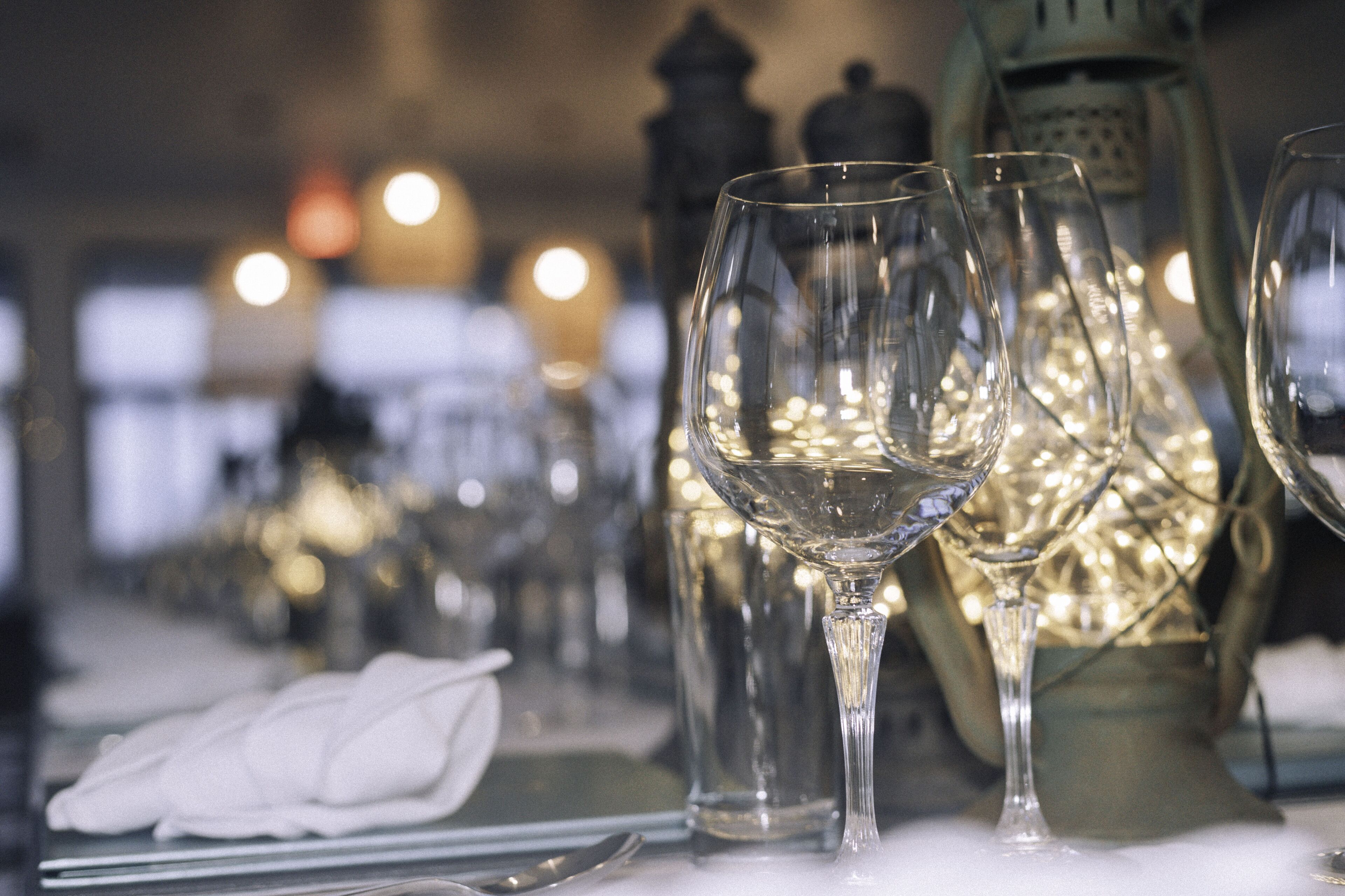 Una mesa dispuesta con copas de vino transparentes, una servilleta doblada y una cuchara.