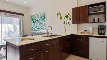 A modern kitchen with dark wooden cabinets, a white countertop, a built-in microwave, and a coffee maker.