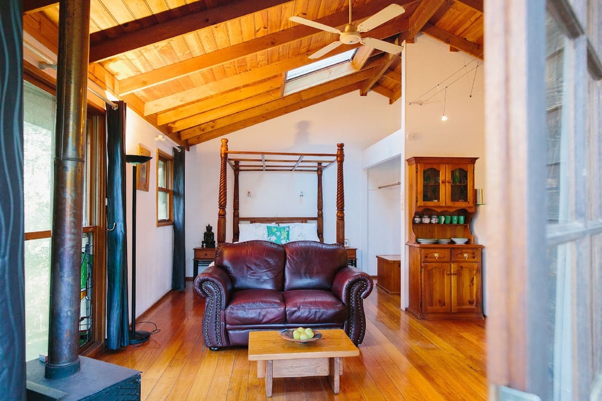 A cozy room with a wooden ceiling, a leather sofa, a wooden table with a bowl, and a wooden cabinet.