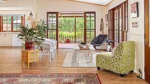 A spacious living area with a large sliding glass door leading to a balcony, a dining table with chairs, a sofa, and a potted plant.