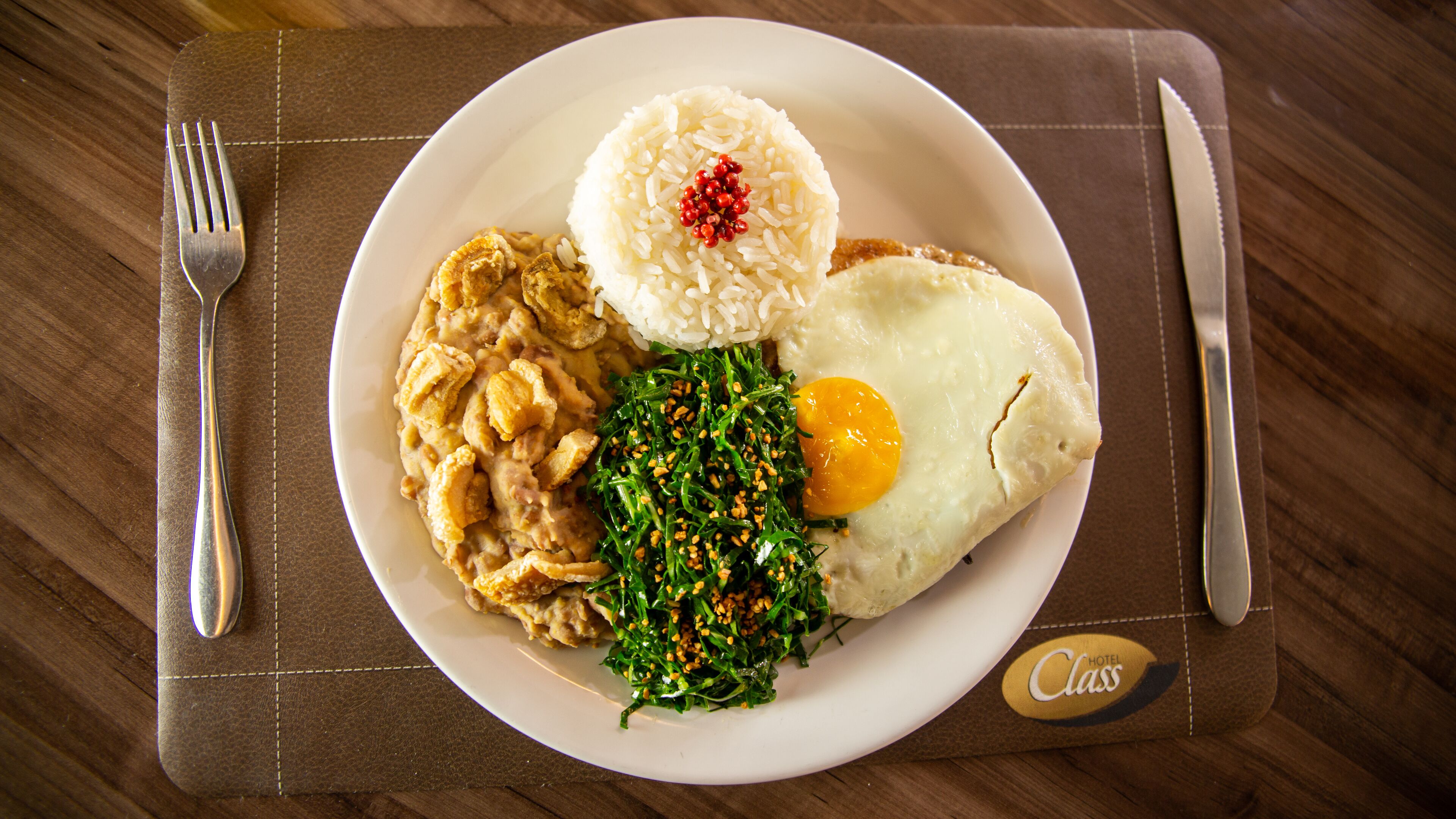 A plate of food with rice, a fried egg, and a side dish, served on a placemat.
