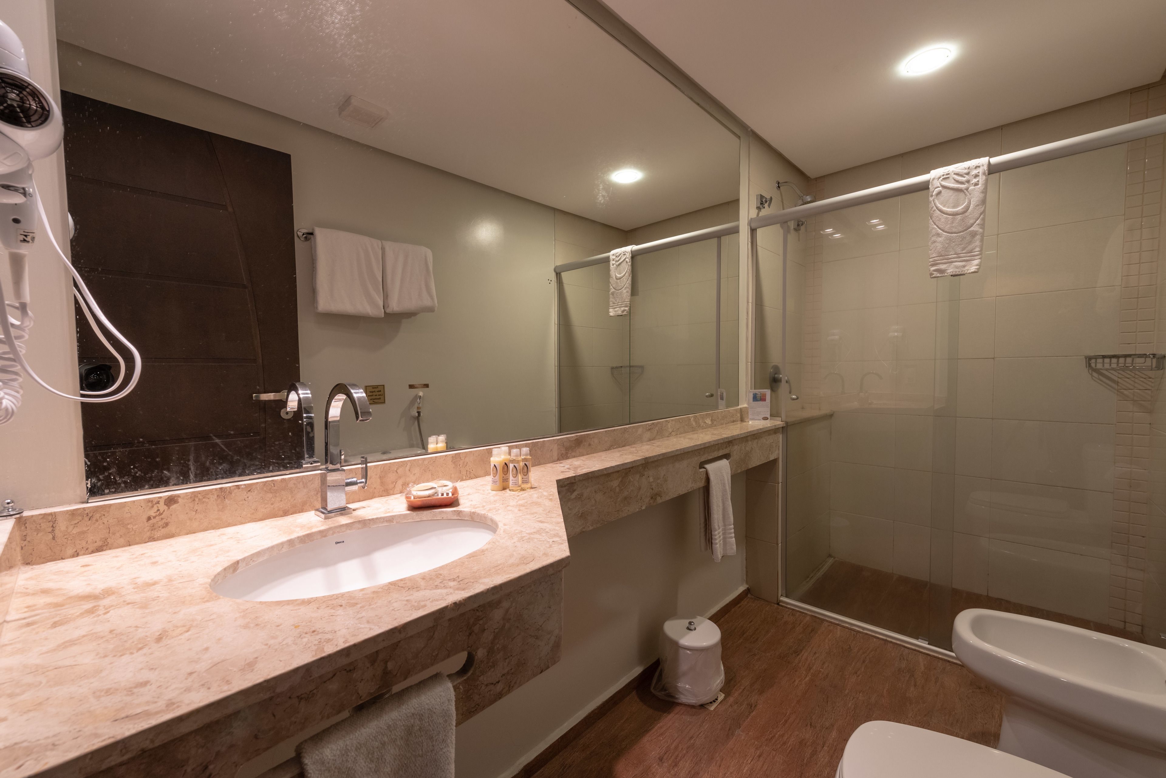 Un baño moderno con lavamanos de mármol, cabina de ducha de vidrio y un inodoro.