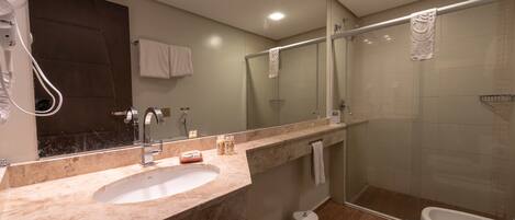 Un baño moderno con lavamanos de mármol, cabina de ducha de vidrio y un inodoro.
