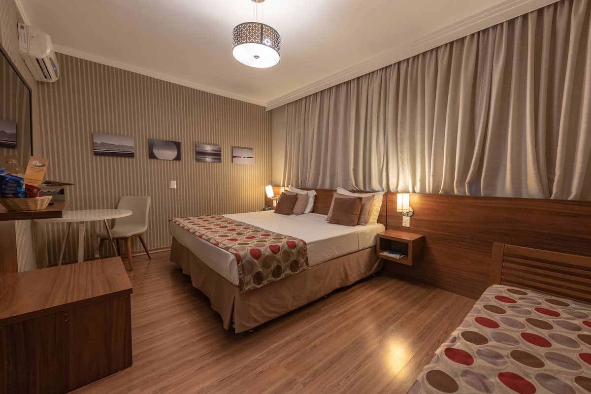 Una habitación de hotel con una cama grande, mesitas de noche, un escritorio y una silla.