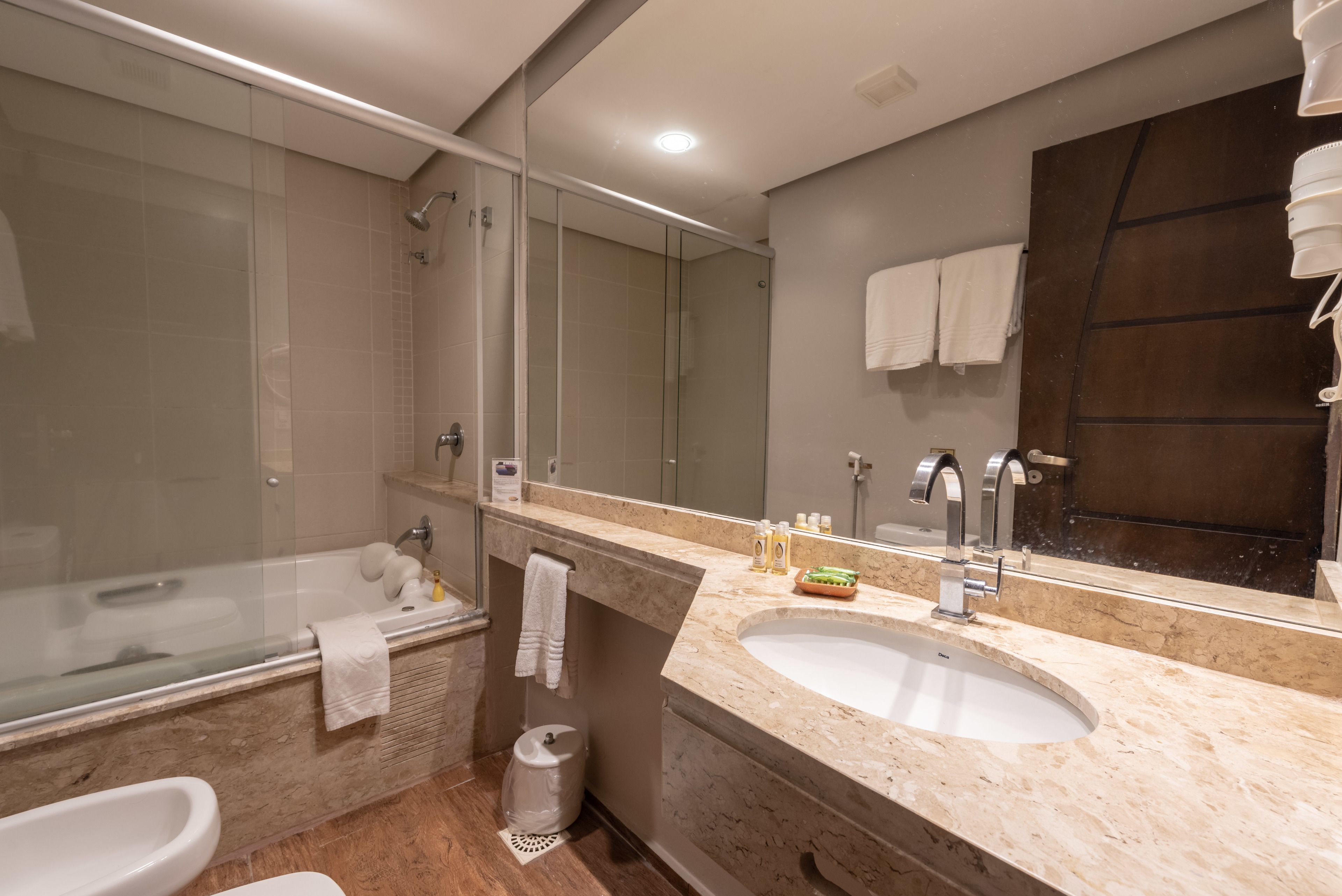 Un baño moderno con ducha envuelta en vidrio, un lavamanos y un espejo grande.