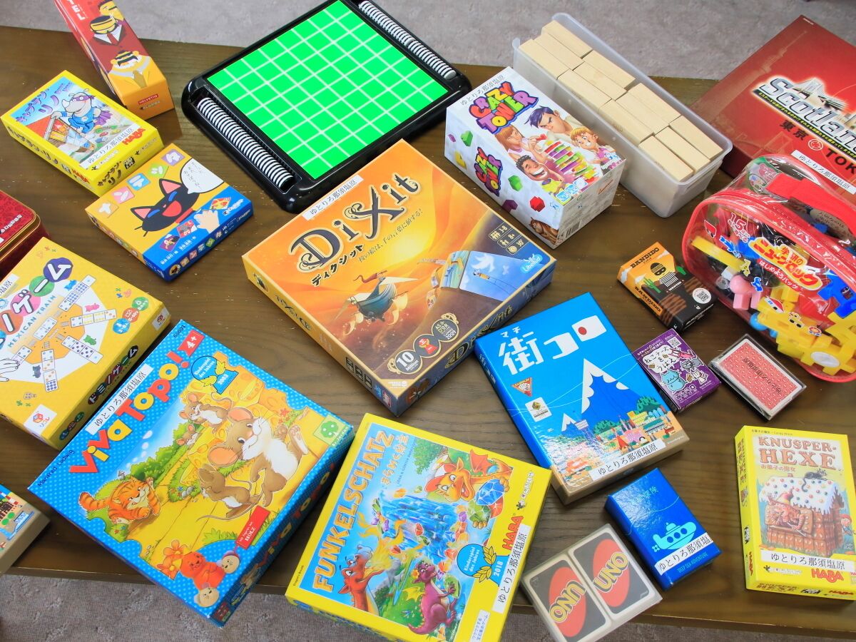 A variety of board games and game boxes on a wooden table.