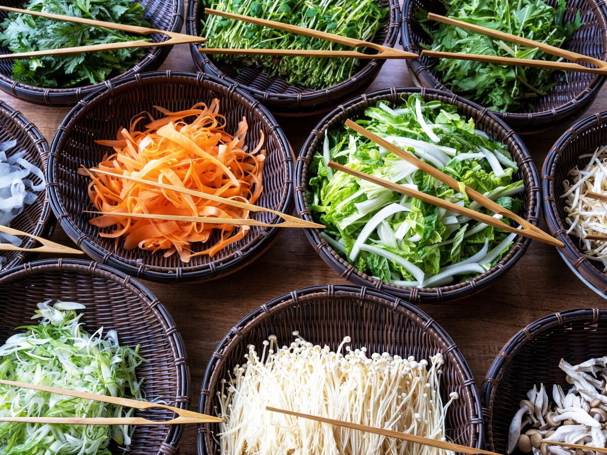 A variety of fresh vegetables in baskets, including carrots, lettuce, and mushrooms.