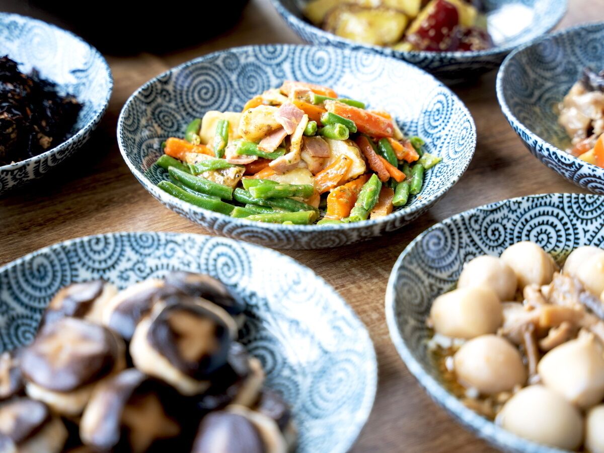 A variety of dishes in patterned bowls, including vegetables and mushrooms.