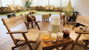 Een gezellige zithoek met houten stoelen en tafels, een groot raam en een tipi decoratie.