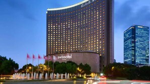 Een hoog hotel met een gebogen gevel, meerdere verdiepingen en opvallende borden met 'Swissotel Living'.