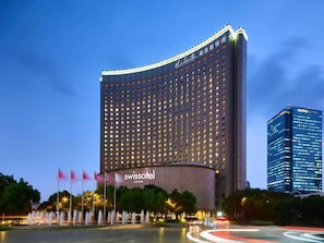 Un hôtel de grande hauteur à la façade incurvée, doté de nombreux étages et d’une enseigne bien visible indiquant « Swissotel Living ».