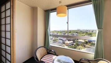 A room with a view of a residential area, a sliding door, and two chairs with cushions.