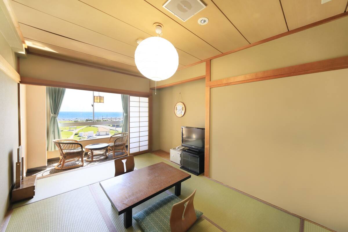 A traditional Japanese room with tatami flooring, a low table, and a television.