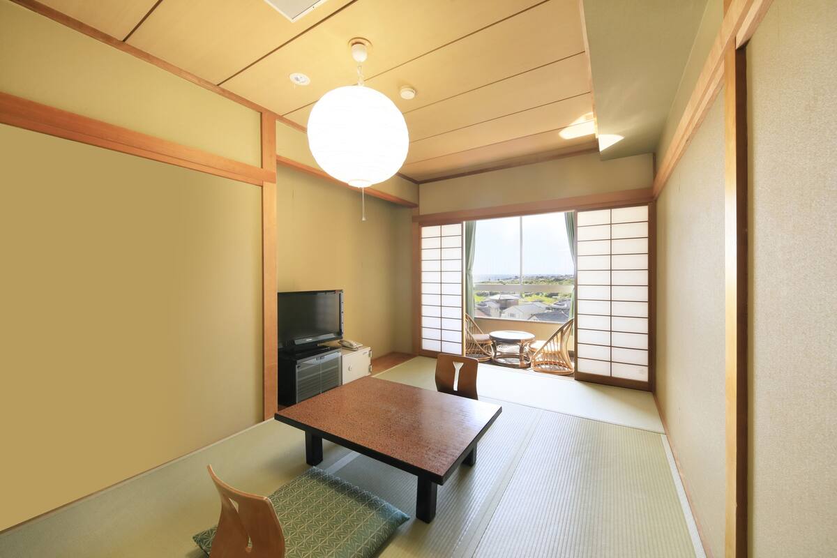 A traditional Japanese room with tatami flooring, a low table, and sliding doors.