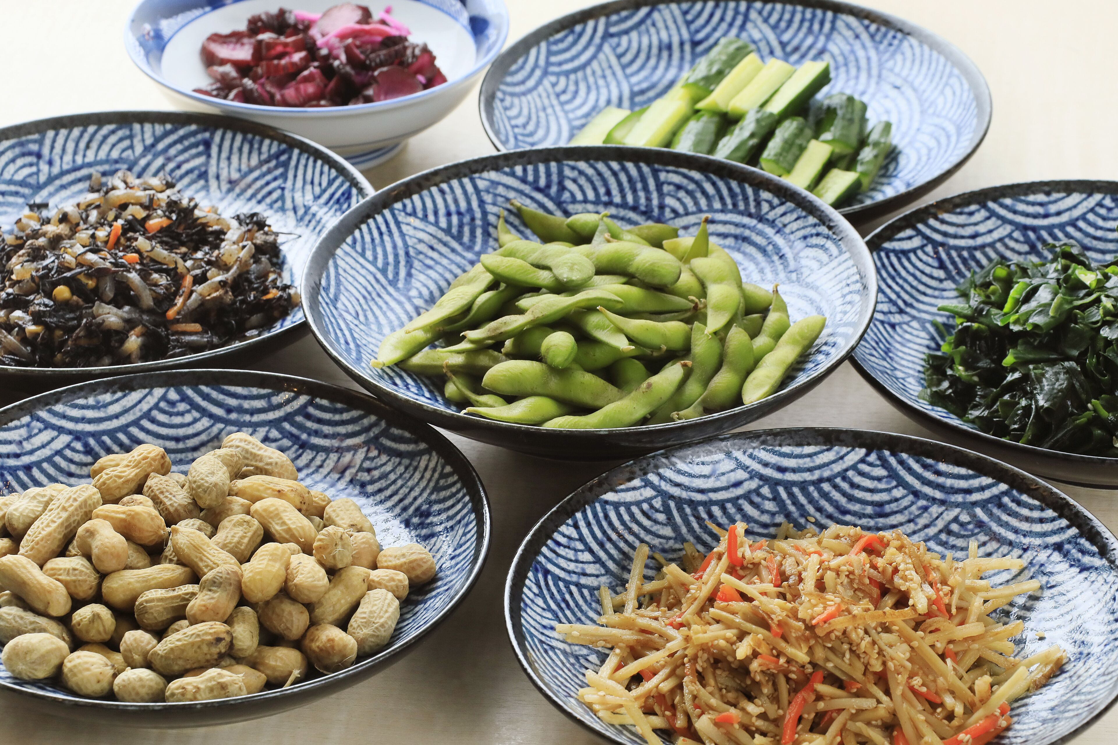 A table with various dishes including edamame, pickled vegetables, and a salad.