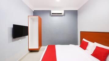 Quarto de hotel com cama, televisão fixada na parede e aparelho de ar condicionado.
