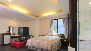 A modern bedroom with a bed, a desk, a chair, and a small kitchenette. - Tai An Cingjing (Zhushan)