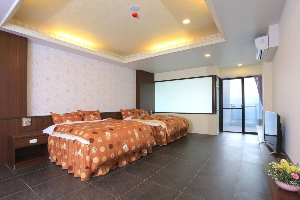 A hotel room with a large bed, a TV, and a balcony with a view.